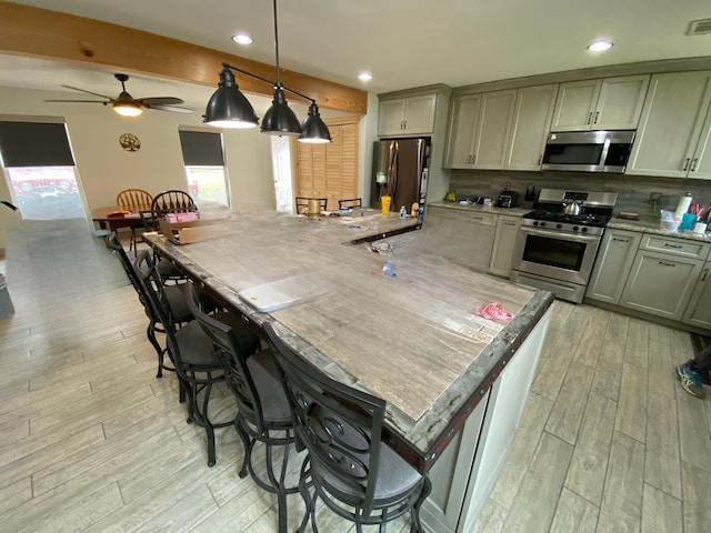 kitchen featuring ceiling fan, gray cabinets, hanging light fixtures, and appliances with stainless steel finishes