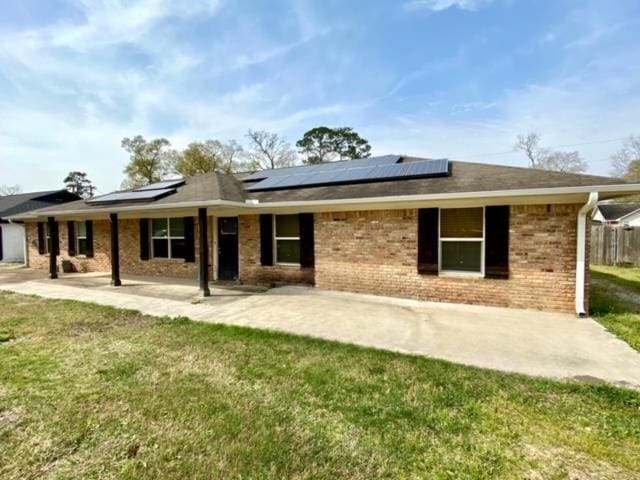 rear view of house featuring solar panels, a patio, and a lawn