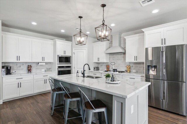 14770 Bond Rd, Beaumont, TX 77713 - kitchen with white cabinetry, appliances with stainless steel finishes, custom range hood, pendant lighting, and a kitchen island with sink