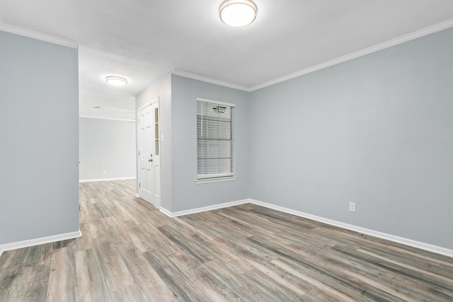 empty room featuring crown molding, baseboards, and wood finished floors