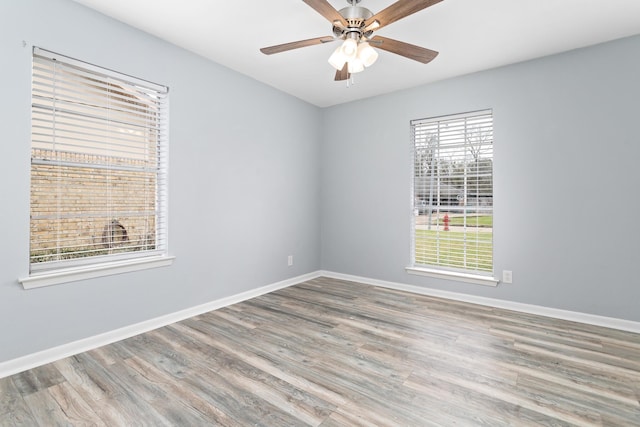 spare room with ceiling fan, wood finished floors, and baseboards