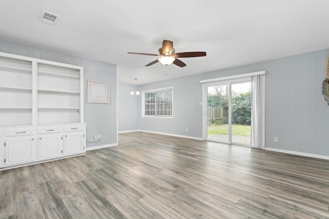 unfurnished living room with light wood-type flooring, visible vents, baseboards, and ceiling fan with notable chandelier