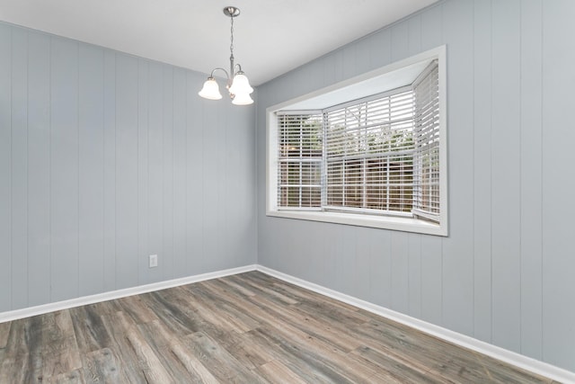 unfurnished room featuring a notable chandelier, baseboards, and wood finished floors