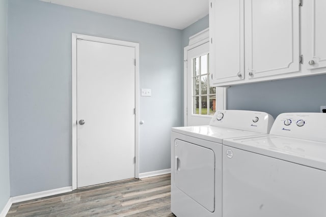 laundry area featuring light wood-style floors, washer and dryer, cabinet space, and baseboards