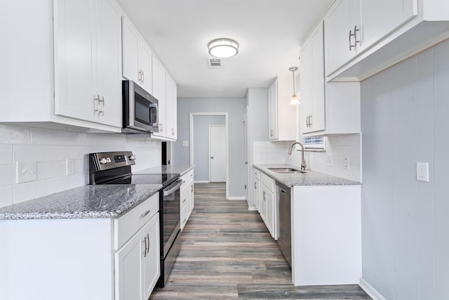 kitchen featuring wood finished floors, stainless steel appliances, light stone counters, and a sink