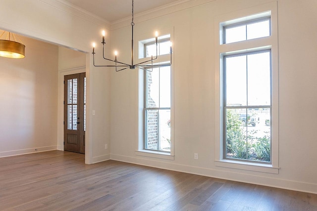 interior space with a notable chandelier, a healthy amount of sunlight, ornamental molding, and dark wood-type flooring