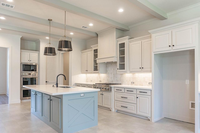 kitchen featuring stainless steel appliances, sink, beam ceiling, a center island with sink, and white cabinetry