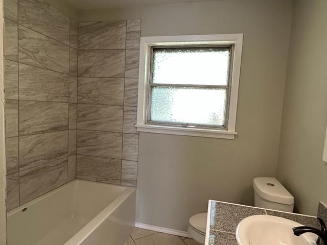 full bathroom with tile patterned flooring, tiled shower / bath combo, toilet, and vanity