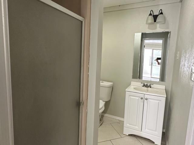 bathroom featuring tile patterned floors, vanity, toilet, and walk in shower