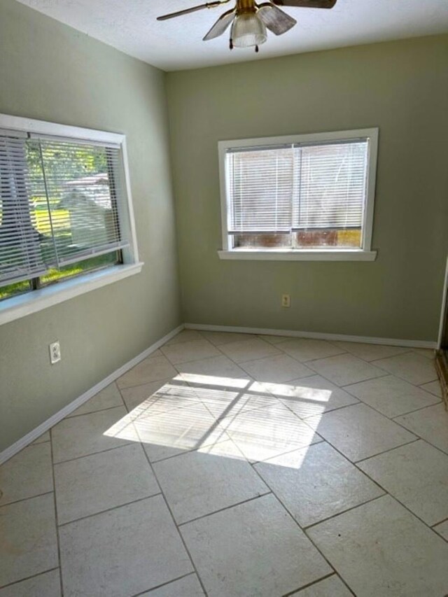 tiled spare room with plenty of natural light and ceiling fan