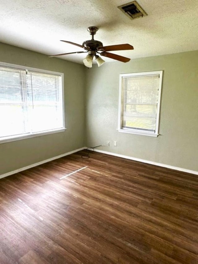 empty room with ceiling fan, dark hardwood / wood-style floors, and a textured ceiling