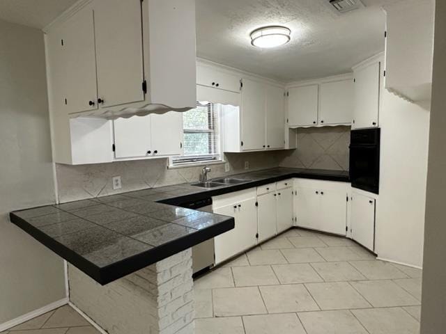 kitchen featuring kitchen peninsula, tasteful backsplash, dishwasher, white cabinets, and oven