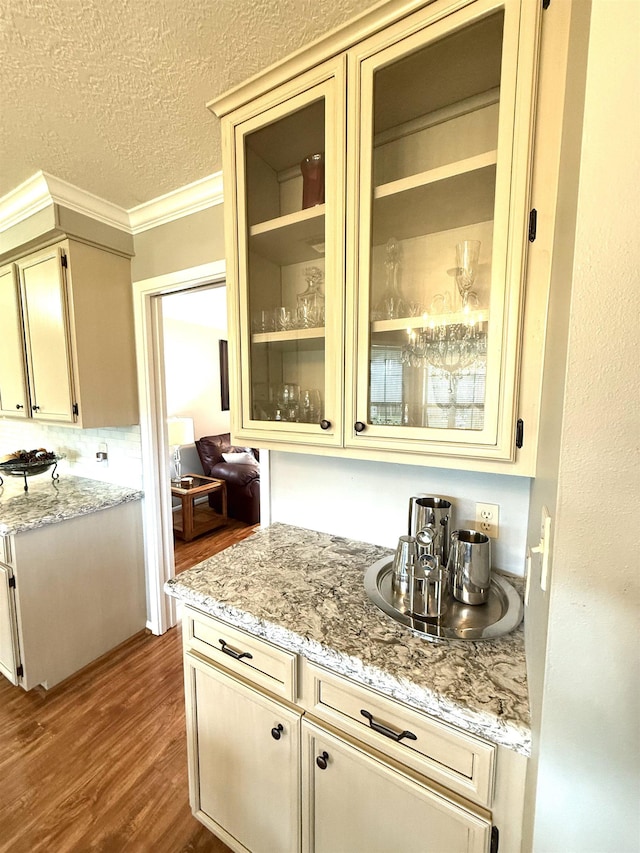2521 Maple St, Nederland, TX 77627 - kitchen with dark wood-style flooring, crown molding, a textured ceiling, glass insert cabinets, and cream cabinets