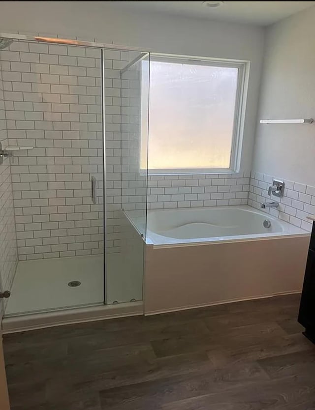 bathroom with wood-type flooring and shower with separate bathtub