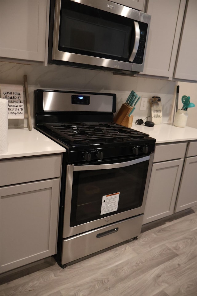 kitchen featuring stainless steel appliances, gray cabinetry, and light hardwood / wood-style flooring