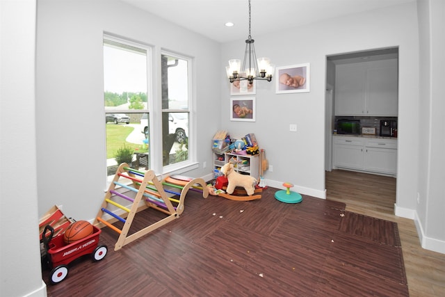 recreation room with a notable chandelier and dark hardwood / wood-style floors