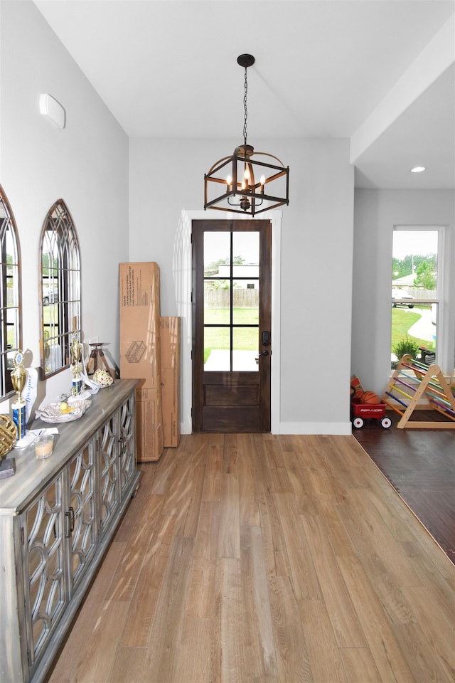 foyer with light wood-type flooring, a wealth of natural light, and a chandelier