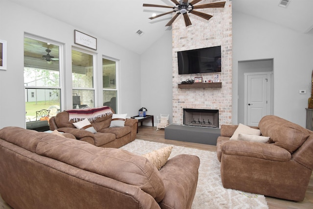 living room featuring light wood-type flooring, a brick fireplace, ceiling fan, and lofted ceiling