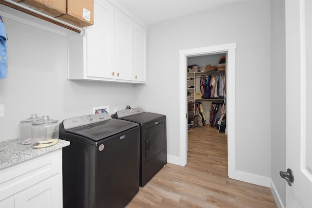 laundry area with cabinets, washing machine and dryer, and light hardwood / wood-style flooring