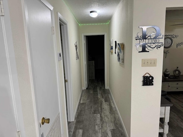 hallway featuring a textured ceiling, dark hardwood / wood-style floors, and crown molding