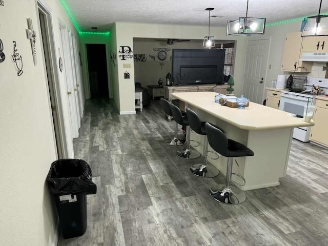 kitchen with pendant lighting, a breakfast bar, white electric stove, a textured ceiling, and a kitchen island