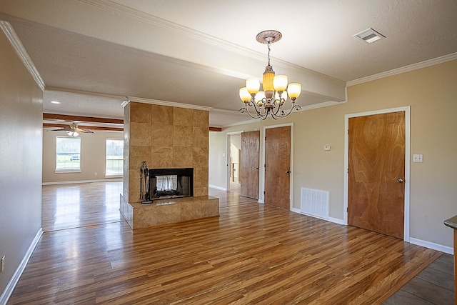 unfurnished living room featuring wood-type flooring, a textured ceiling, ceiling fan with notable chandelier, a fireplace, and ornamental molding