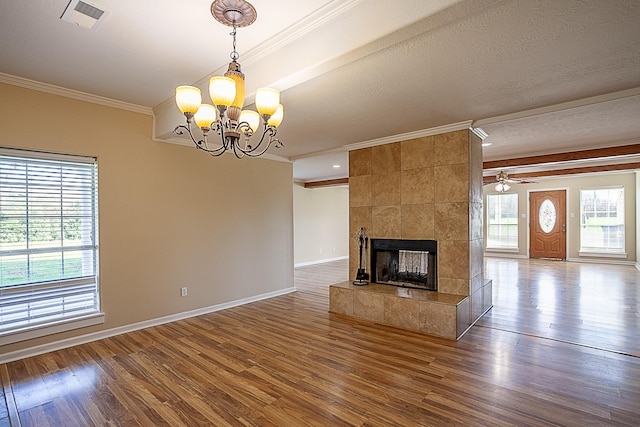 unfurnished living room featuring a textured ceiling, a tile fireplace, crown molding, and wood-type flooring