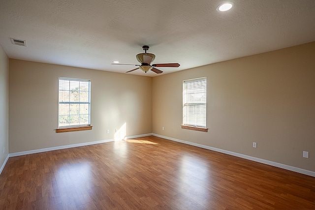 spare room featuring hardwood / wood-style flooring, ceiling fan, and a textured ceiling