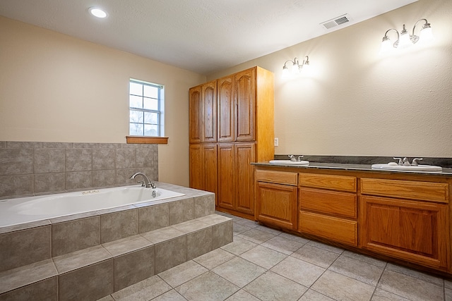 bathroom featuring tile patterned floors, vanity, and a relaxing tiled tub