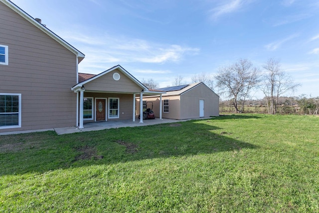 rear view of property with a patio, a yard, and an outbuilding