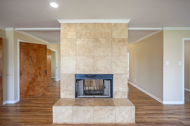 details featuring a textured ceiling, ornamental molding, a tile fireplace, and wood-type flooring