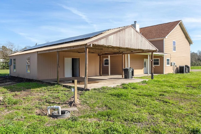 rear view of house with a patio, solar panels, a lawn, and central air condition unit