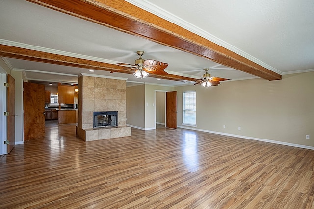 unfurnished living room with light hardwood / wood-style flooring, ornamental molding, beam ceiling, and a fireplace