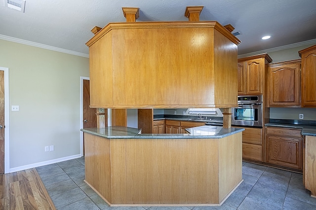 kitchen with stainless steel oven, sink, ornamental molding, and kitchen peninsula