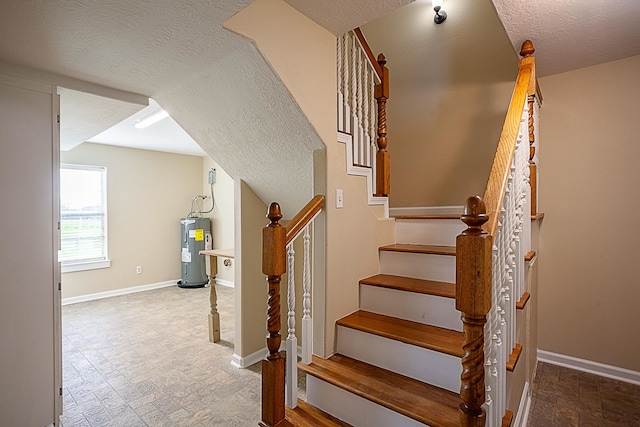 staircase with electric water heater and a textured ceiling