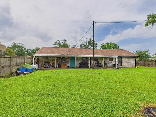 back of property featuring brick siding, a yard, and a fenced backyard
