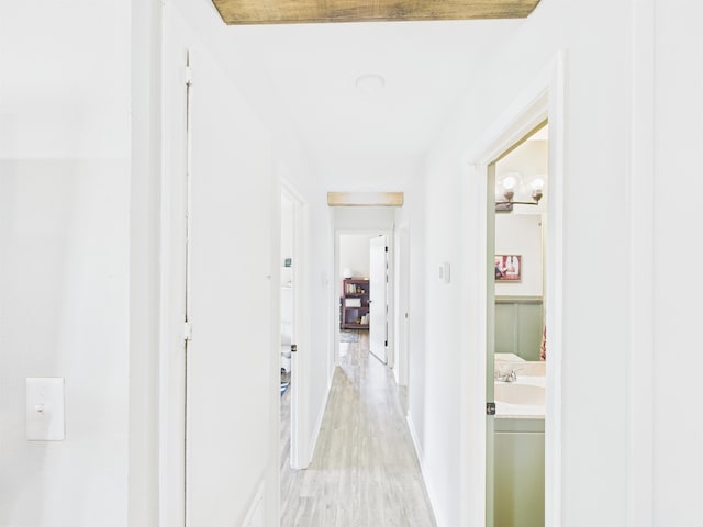 hall featuring light wood-style flooring and baseboards