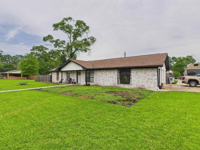 ranch-style home with brick siding, a shingled roof, and a front lawn