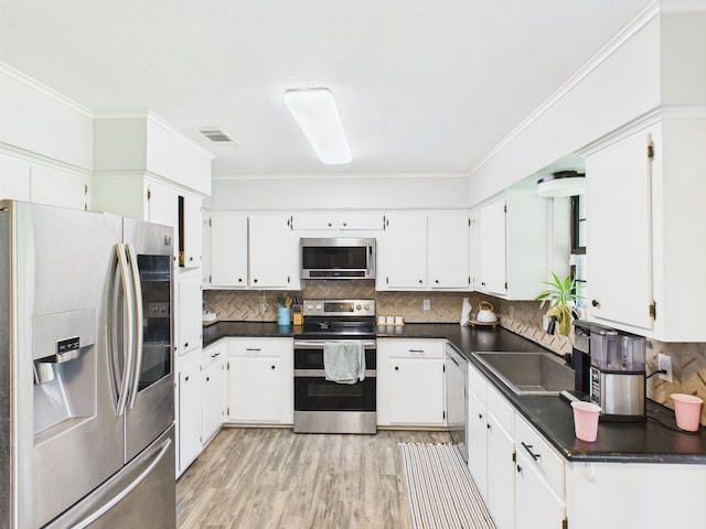 kitchen featuring visible vents, stainless steel appliances, dark countertops, backsplash, and light wood-type flooring