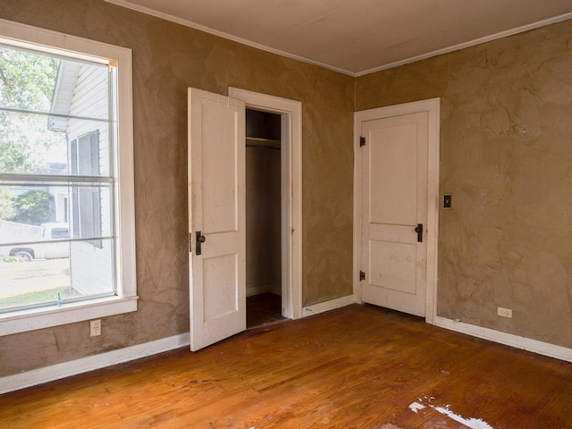 unfurnished bedroom featuring wood-type flooring, a closet, and ornamental molding