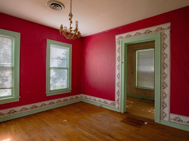 unfurnished room featuring a chandelier and wood-type flooring