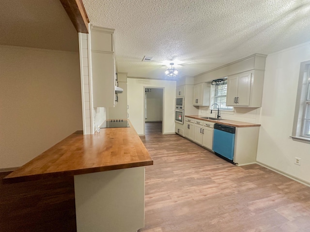 kitchen featuring dishwashing machine, butcher block counters, and light wood-style flooring