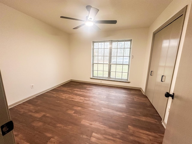 unfurnished bedroom with a ceiling fan, a closet, dark wood finished floors, and baseboards