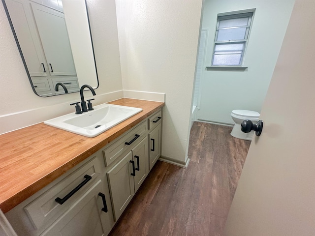 bathroom with toilet, wood finished floors, and vanity