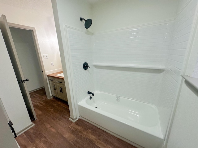 full bathroom with a textured ceiling, vanity, shower / bathtub combination, and wood finished floors