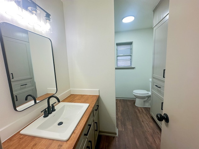 bathroom featuring toilet, baseboards, wood finished floors, and vanity