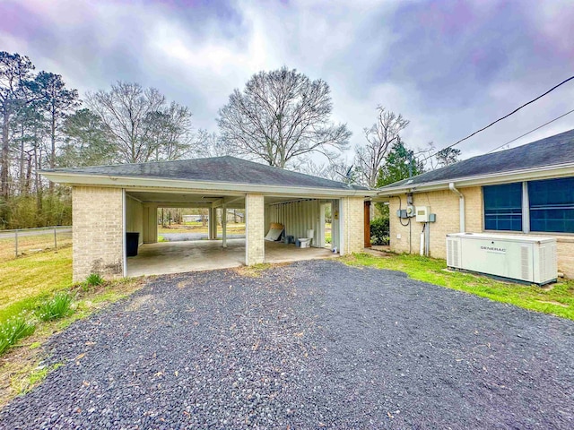 view of vehicle parking with gravel driveway, fence, and a carport