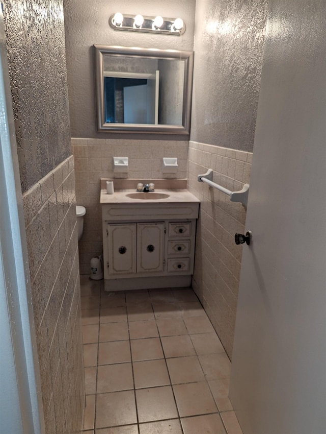 bathroom featuring toilet, vanity, tile patterned floors, and tile walls