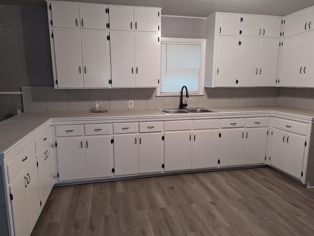 kitchen with light wood-type flooring, white cabinetry, and sink