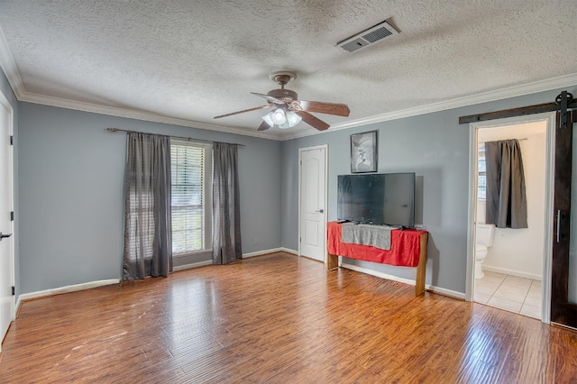 living room with crown molding, hardwood / wood-style flooring, ceiling fan, a barn door, and a textured ceiling